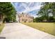 A brick two-story home with a long driveway and side entry garage, nestled in a lush green landscape at 105 Kellens Ct, Fayetteville, GA 30215