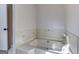Neutral toned bathtub with tiled surround and a glimpse of the doorway in background at 1355 Compton Woods Dr, Loganville, GA 30052