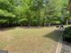 Large, grassy backyard extending into a wooded area, offering a peaceful retreat with patio space and outdoor seating at 616 Wallnut Hall Tl, Woodstock, GA 30189