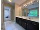 Spacious bathroom featuring double sink vanity, framed mirror with decorative lighting, and accessible doorway at 616 Wallnut Hall Tl, Woodstock, GA 30189
