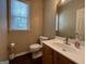 Well-lit half bathroom with a white toilet, vanity with a mirror, and neutral walls at 616 Wallnut Hall Tl, Woodstock, GA 30189