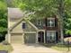 Charming home featuring a two-car garage, manicured lawn, and a mix of brick and siding accents at 616 Wallnut Hall Tl, Woodstock, GA 30189