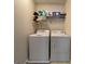 Bright laundry room with front-load washer and dryer, storage shelf, and tile flooring at 616 Wallnut Hall Tl, Woodstock, GA 30189