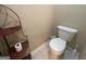 Standard toilet with white porcelain and a brown wicker shelving unit beside it on tiled floor at 616 Wallnut Hall Tl, Woodstock, GA 30189
