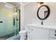 Bathroom featuring a glass-enclosed shower, sleek white vanity, and decorative round mirror at 760 Swan Ln, Canton, GA 30115