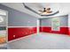 Spacious carpeted bedroom with red accent wall, tray ceiling, and ceiling fan with light fixture at 227 River Trace Ct, Mcdonough, GA 30253