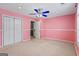 Pink-walled bedroom features a large closet, a door to the bathroom, a window, and a ceiling fan with light fixture at 227 River Trace Ct, Mcdonough, GA 30253
