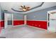 Spacious carpeted bedroom with red accent wall, tray ceiling, ceiling fan, and access to the closet at 227 River Trace Ct, Mcdonough, GA 30253