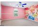 This pink-walled bedroom features a Disney princess mural, a window with natural light, and a ceiling fan at 227 River Trace Ct, Mcdonough, GA 30253