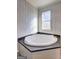 Bright bathroom featuring a corner tub with dark countertop, complemented by a window for natural light at 36 Highpoint Ln, Locust Grove, GA 30248