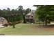 Beautiful home nestled among tall trees, featuring a well-kept lawn and lovely flower beds at 166 Nobility Ln, Mcdonough, GA 30252
