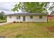 Charming, one-story home with brick accents, a well-manicured lawn, and lush greenery at 7279 Mayfair Cir, Jonesboro, GA 30236