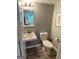 Bathroom featuring a sleek sink, toilet, wood-look floors, and well-lit mirror at 2691 Old South Dr, Jonesboro, GA 30236