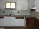 Image of a kitchen with worn white cabinets, stainless steel sink, and small window at 6186 Green Acres Sw Dr, Covington, GA 30014