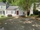 Charming home featuring a red front door, white siding, black shutters, and mature landscaping at 1047 Plantation Nw Way, Kennesaw, GA 30144