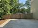 A private backyard features a wooden fence and a spacious concrete patio area surrounded by mature trees at 30 Wellington Trl, Covington, GA 30016