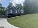 Side view of well-manicured lawn of gray home with a long driveway leading up to attached garage at 30 Wellington Trl, Covington, GA 30016