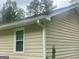Close-up of the home's exterior showcasing light-colored siding, a window, and well-maintained gutters at 625 Locust Rd, Locust Grove, GA 30248