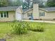 Exterior view of the home featuring a garage, well-manicured lawn, and vibrant flowerbeds at 625 Locust Rd, Locust Grove, GA 30248