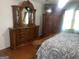 Bedroom with traditional wooden furniture set, including a dresser with mirror and TV on top of wardrobe at 625 Locust Rd, Locust Grove, GA 30248