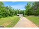 A single-story home sits on a large lawn with a long driveway and is surrounded by abundant trees and greenery at 3775 Highway 16 E, Sharpsburg, GA 30277