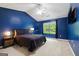 The main bedroom showcases a large bed, blue walls, vaulted ceiling, and natural light from the window at 3775 Highway 16 E, Sharpsburg, GA 30277
