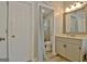 Bright bathroom featuring a wooden vanity, modern mirror, and a view of the tiled shower at 175 Thomas Overby Dr, Sharpsburg, GA 30277