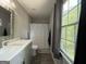 Bright bathroom with large window, shower with curtain, and gray vanity with sink at 3456 Village Glen Ct, Snellville, GA 30039