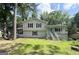 Charming two-story home with a front yard and a blue door on the porch, surrounded by lush trees at 3456 Village Glen Ct, Snellville, GA 30039