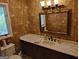 Cozy bathroom featuring faux stone walls, decorative mirror, and traditional vanity with dark wood cabinets at 205 Aberdeen Dr, Peachtree City, GA 30269