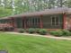Ranch style home featuring a covered front porch with stone supports, and front yard landscaping at 205 Aberdeen Dr, Peachtree City, GA 30269