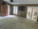Spacious living room with a wall-mounted TV, neutral carpeting, and a door that leads outdoors at 205 Aberdeen Dr, Peachtree City, GA 30269