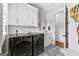 Laundry room with white cabinets, decorative mirror, modern appliances, and an adjacent door to another room at 215 Sheridan Ln, Peachtree City, GA 30269