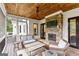 Cozy covered porch with stone fireplace, tv, and comfortable seating, perfect for relaxing or entertaining guests at 215 Sheridan Ln, Peachtree City, GA 30269