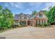 Stately brick home with a circular driveway, manicured landscaping, and charming balcony details at 95 Weslyan Way, Oxford, GA 30054