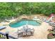 Aerial view of private pool with waterfall feature, dining table and multiple lounge chairs surrounded by forest at 95 Weslyan Way, Oxford, GA 30054