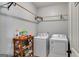 Efficient laundry room featuring a washer, dryer, wooden storage rack, and hanging rod at 127 Grayson Myers Dr, Villa Rica, GA 30180