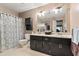 Well-lit bathroom with a double vanity, decorative mirror, and patterned shower curtain at 2371 Leguin Mill Rd, Locust Grove, GA 30248
