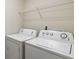 Compact laundry room with white washer and dryer, plus wire shelving for storage solutions at 5396 Pennington Ct, South Fulton, GA 30349