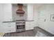 Well-lit kitchen featuring stainless steel oven, custom range hood, stylish backsplash, and white cabinets at 185 Chimney Springs, Tyrone, GA 30290