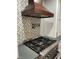 Stylish kitchen range with decorative backsplash, pot filler, custom range hood, and granite countertop at 185 Chimney Springs, Tyrone, GA 30290