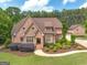 Stunning brick home with manicured landscaping, mature trees, long driveway, and a guest house on a beautiful day at 210 Short Rd, Sharpsburg, GA 30277