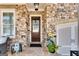 Inviting front porch with stone accents, a cozy seating area, and beautiful landscaping around the entrance at 10140 Grandview Sq, Duluth, GA 30097