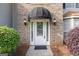 Close-up of a white front door with a black awning and sidelights, framed by brick and landscaping at 3941 Kings Pl, Ellenwood, GA 30294