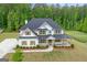 Charming two-story home featuring white siding, black roof, and inviting front porch, surrounded by greenery at 152 Creekrise Pl, Palmetto, GA 30268