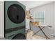 Efficient laundry room with modern, front loading washer/dryer, ironing board, and storage at 152 Creekrise Pl, Palmetto, GA 30268