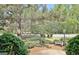 Landscaped front yard with bushes, a small bench, and a view of mature trees on a sunny day at 401 Waterwood Bnd, Peachtree City, GA 30269