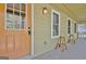 Covered porch with an orange front door and two counter stools next to white framed windows at 401 Waterwood Bnd, Peachtree City, GA 30269