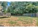 Grassy backyard with a wooden deck, playset with swings, and surrounding tall trees and wooden fence at 127 Muirwood Dr, Temple, GA 30179