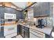 Well-lit kitchen with black cabinets, modern appliances, and unique corrugated metal backsplash at 127 Muirwood Dr, Temple, GA 30179